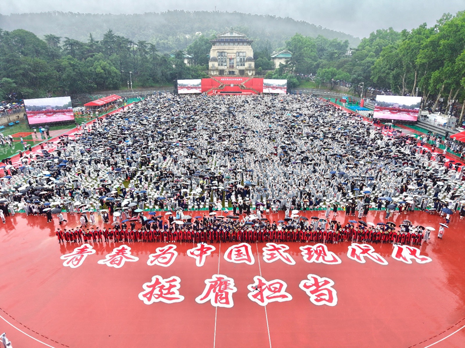 武大校长在雨中配合毕业生拍照，还拿娃娃、“比耶”，询问就业情况